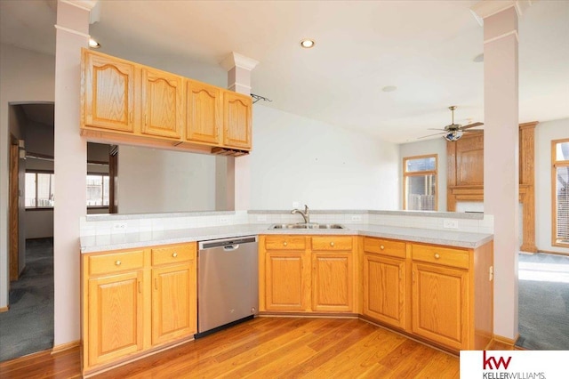 kitchen featuring a peninsula, a sink, light countertops, dishwasher, and a wealth of natural light