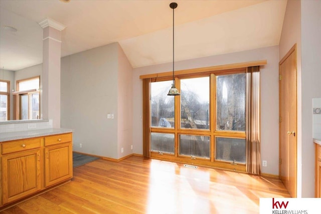 unfurnished dining area featuring light wood-style flooring, decorative columns, baseboards, and visible vents