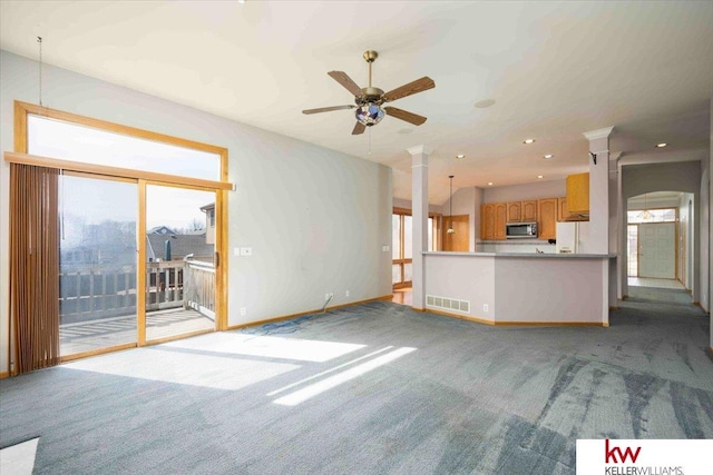 unfurnished living room featuring visible vents, plenty of natural light, carpet floors, and ornate columns