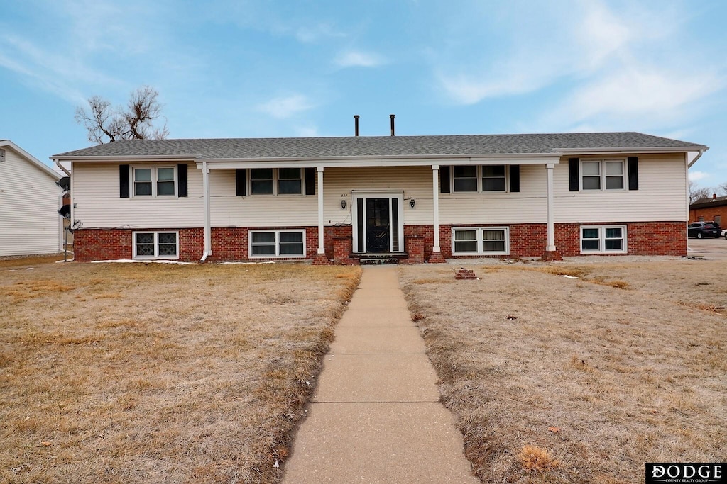 bi-level home featuring a front lawn and brick siding