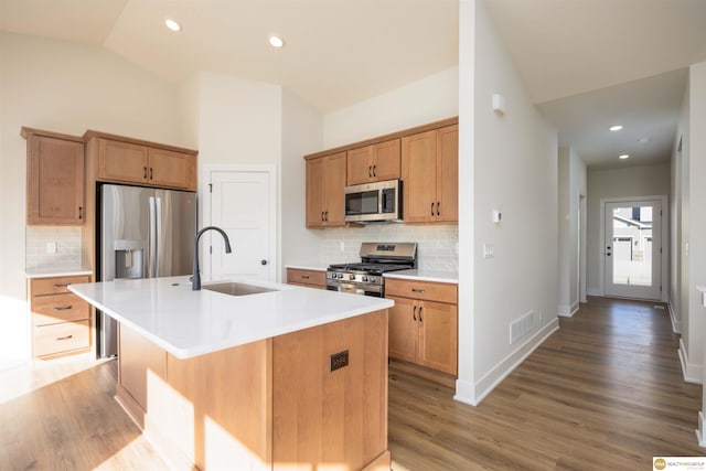 kitchen featuring light wood finished floors, visible vents, appliances with stainless steel finishes, vaulted ceiling, and a sink