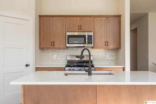 kitchen with a sink, appliances with stainless steel finishes, decorative backsplash, and light countertops