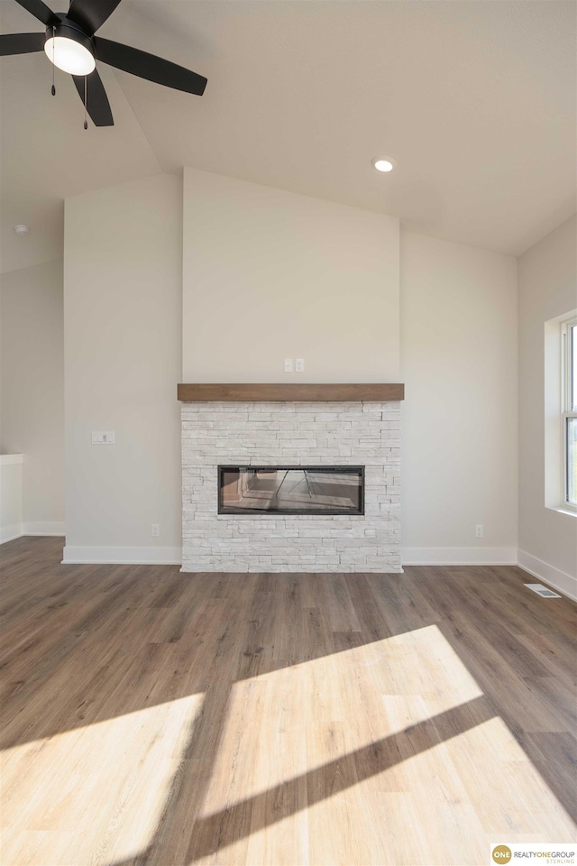 unfurnished living room featuring a stone fireplace, wood finished floors, visible vents, and baseboards