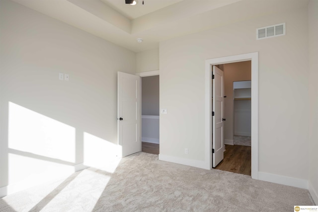 unfurnished bedroom with carpet floors, a walk in closet, visible vents, and baseboards