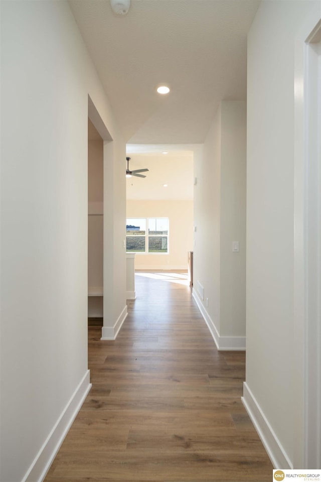 hallway with recessed lighting, visible vents, baseboards, and wood finished floors