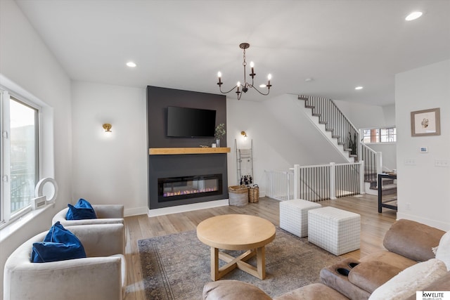 living area featuring recessed lighting, wood finished floors, baseboards, stairway, and a glass covered fireplace