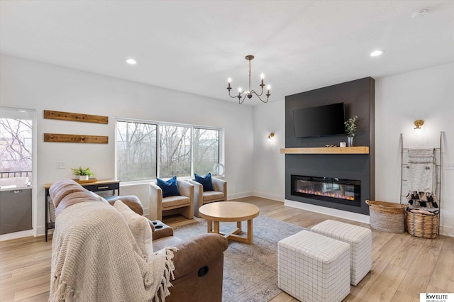 living area with a chandelier, light wood-style flooring, recessed lighting, baseboards, and a glass covered fireplace