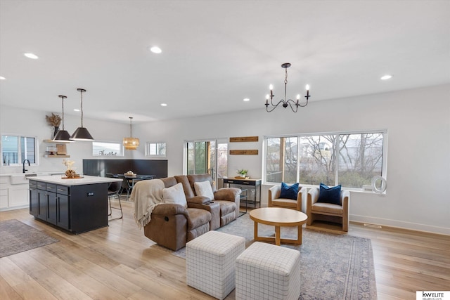 living area with an inviting chandelier, light wood-style flooring, baseboards, and recessed lighting