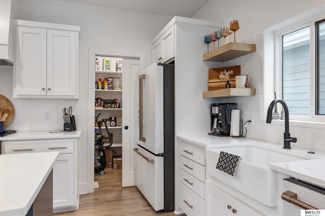 kitchen with high end white refrigerator, a healthy amount of sunlight, open shelves, and a sink