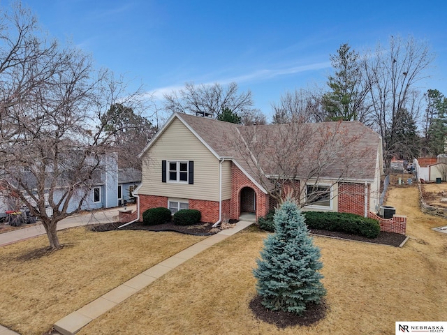 view of front of home featuring a shingled roof, brick siding, and a front lawn