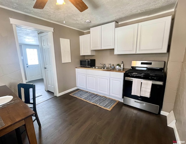 kitchen featuring dark wood-style flooring, appliances with stainless steel finishes, white cabinets, a sink, and a textured ceiling