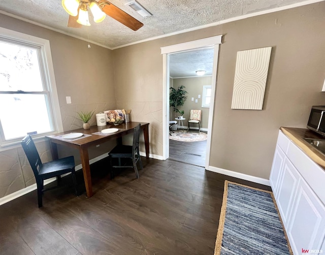 dining space with a textured ceiling, dark wood-type flooring, visible vents, and a healthy amount of sunlight