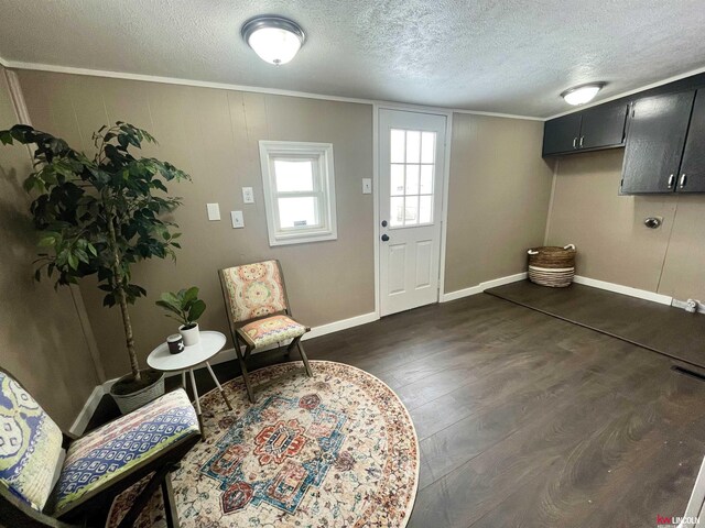 foyer featuring a textured ceiling, baseboards, dark wood-style flooring, and ornamental molding