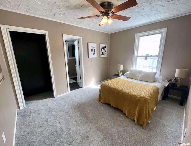 bedroom with a textured ceiling, carpet floors, ornamental molding, and ceiling fan