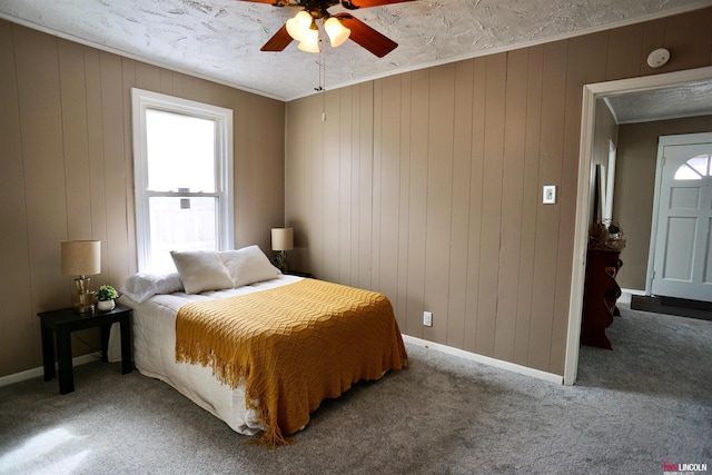 carpeted bedroom featuring ornamental molding, ceiling fan, and baseboards