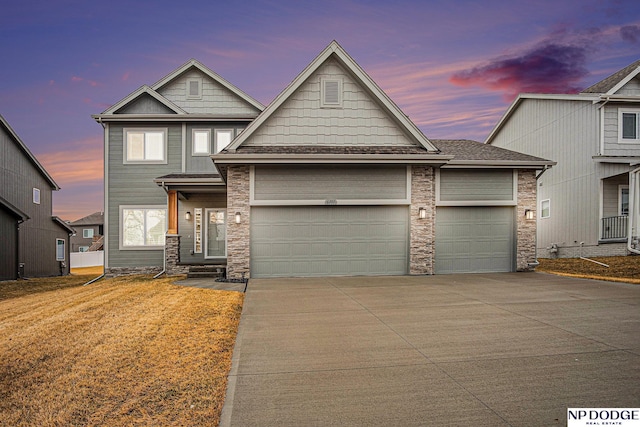 view of front of house with concrete driveway, stone siding, a lawn, and an attached garage