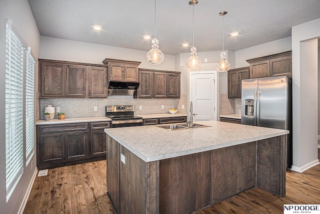 kitchen featuring under cabinet range hood, a sink, dark brown cabinets, appliances with stainless steel finishes, and light countertops