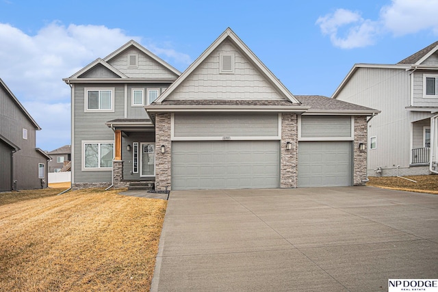 craftsman-style home featuring an attached garage, stone siding, driveway, and a front yard