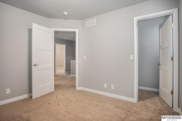 unfurnished bedroom with visible vents, light carpet, and baseboards