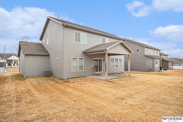 rear view of property featuring roof with shingles, a lawn, central AC, and a patio