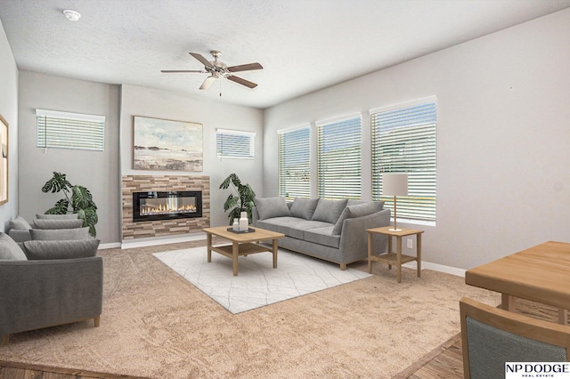 living area with carpet, a ceiling fan, a textured ceiling, and a glass covered fireplace