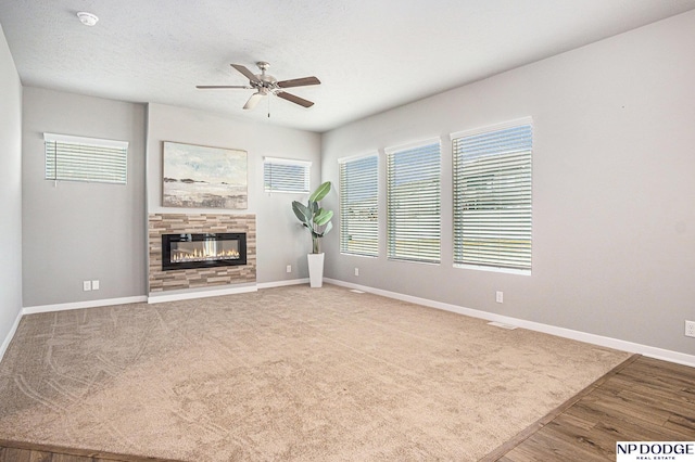 unfurnished living room with a healthy amount of sunlight, carpet floors, baseboards, and a glass covered fireplace