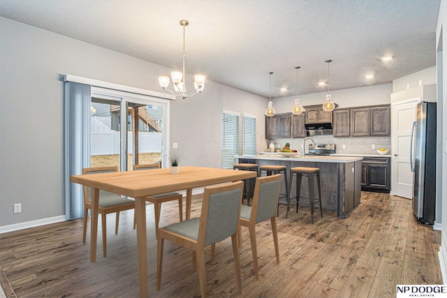 dining space featuring recessed lighting, baseboards, an inviting chandelier, and wood finished floors