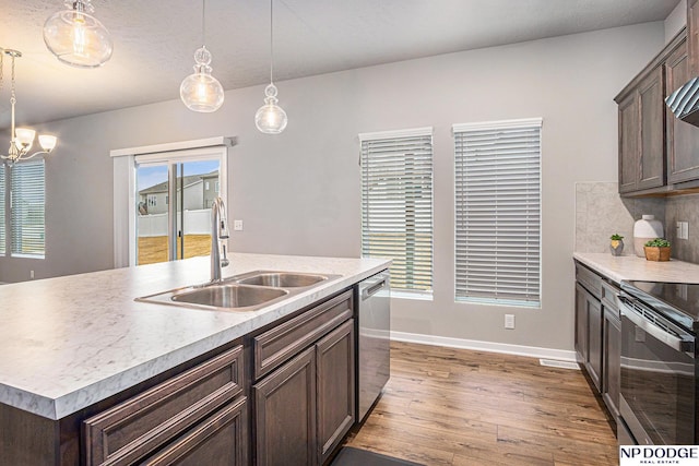 kitchen featuring decorative backsplash, appliances with stainless steel finishes, a sink, dark brown cabinetry, and wood finished floors