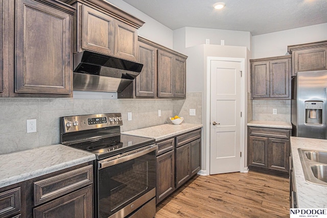 kitchen with dark brown cabinets, appliances with stainless steel finishes, light wood-style flooring, and under cabinet range hood