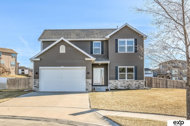 traditional home featuring a garage, concrete driveway, a front lawn, and fence