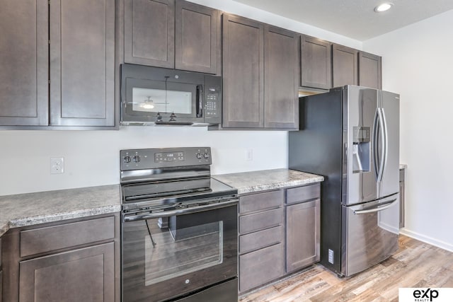 kitchen featuring light countertops, light wood-style flooring, black appliances, dark brown cabinets, and baseboards