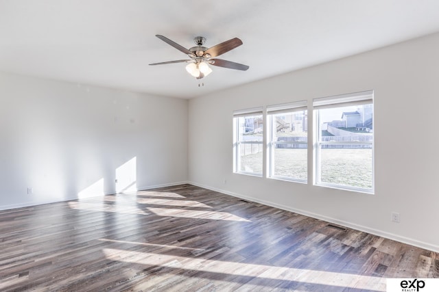 unfurnished room with ceiling fan, wood finished floors, visible vents, and baseboards