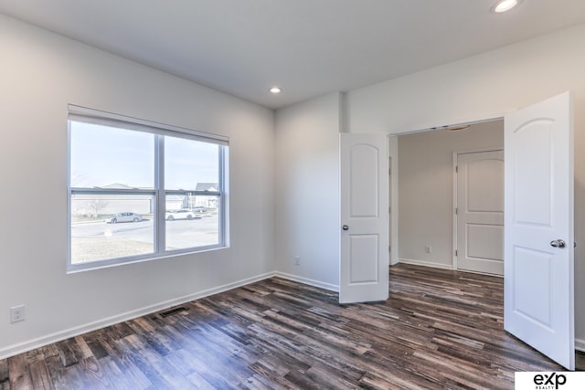 empty room featuring dark wood-type flooring, recessed lighting, visible vents, and baseboards