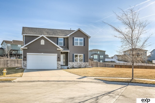 traditional-style home with stone siding, fence, concrete driveway, and a front yard