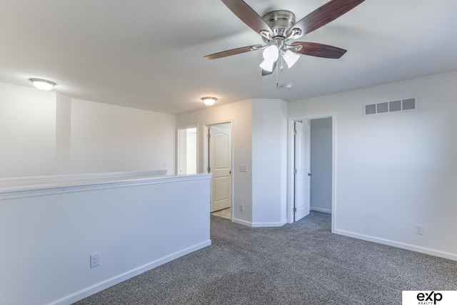 carpeted empty room with baseboards, visible vents, and ceiling fan