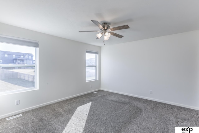 carpeted spare room featuring a ceiling fan, visible vents, and baseboards