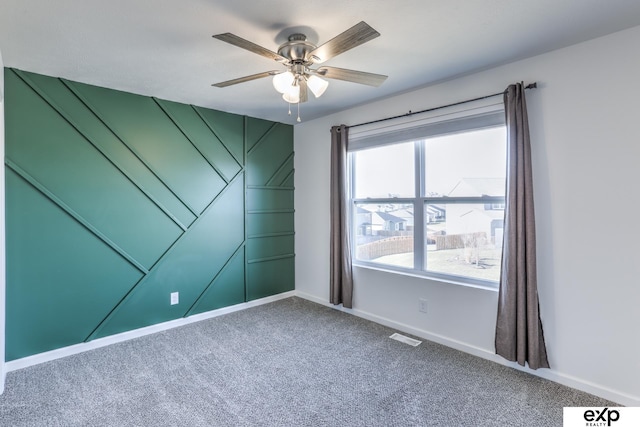 unfurnished room with carpet, visible vents, ceiling fan, and baseboards