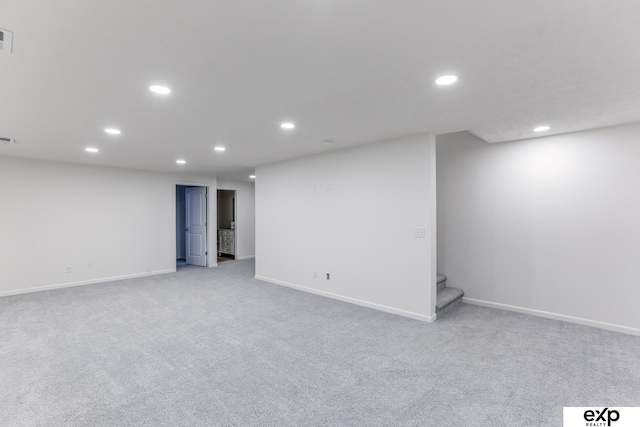 finished below grade area featuring recessed lighting, light carpet, stairway, and baseboards