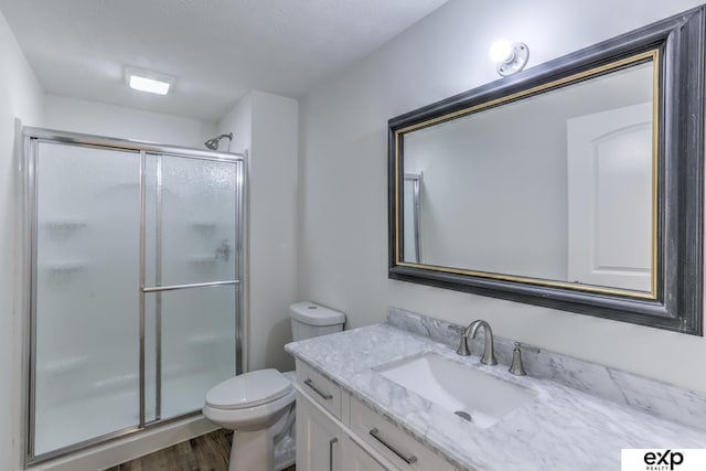 full bathroom featuring a stall shower, vanity, toilet, and wood finished floors