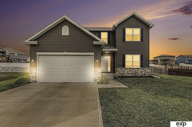 traditional-style house with a garage, driveway, a yard, and fence