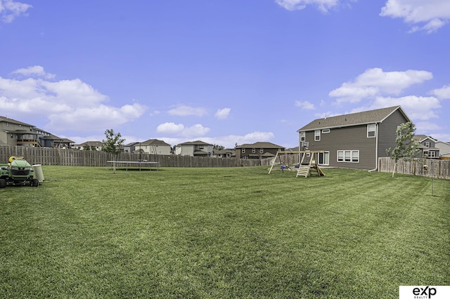 view of yard featuring a trampoline, a playground, a fenced backyard, and a residential view