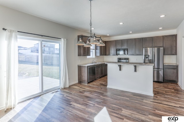 kitchen with dark brown cabinetry, dark wood-style floors, stainless steel appliances, and a center island