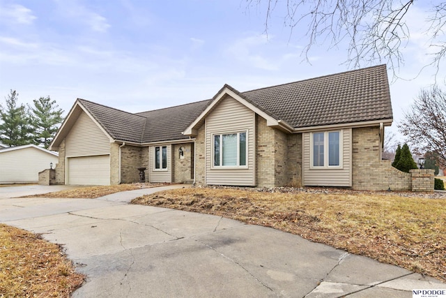 single story home featuring concrete driveway, brick siding, an attached garage, and a tiled roof