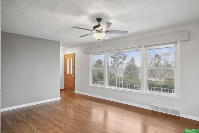 spare room with baseboards, a textured ceiling, visible vents, and wood finished floors