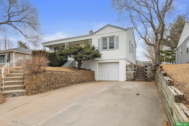 view of front of home featuring an attached garage, stairs, a chimney, and concrete driveway