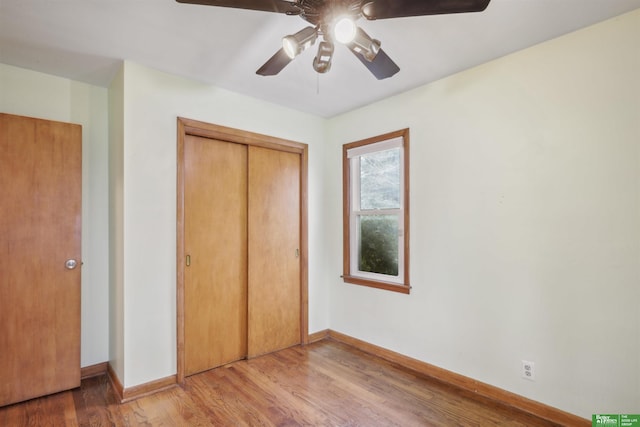 unfurnished bedroom with ceiling fan, a closet, baseboards, and wood finished floors