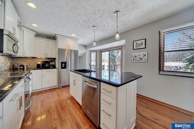 kitchen with dark countertops, light wood finished floors, appliances with stainless steel finishes, and decorative backsplash