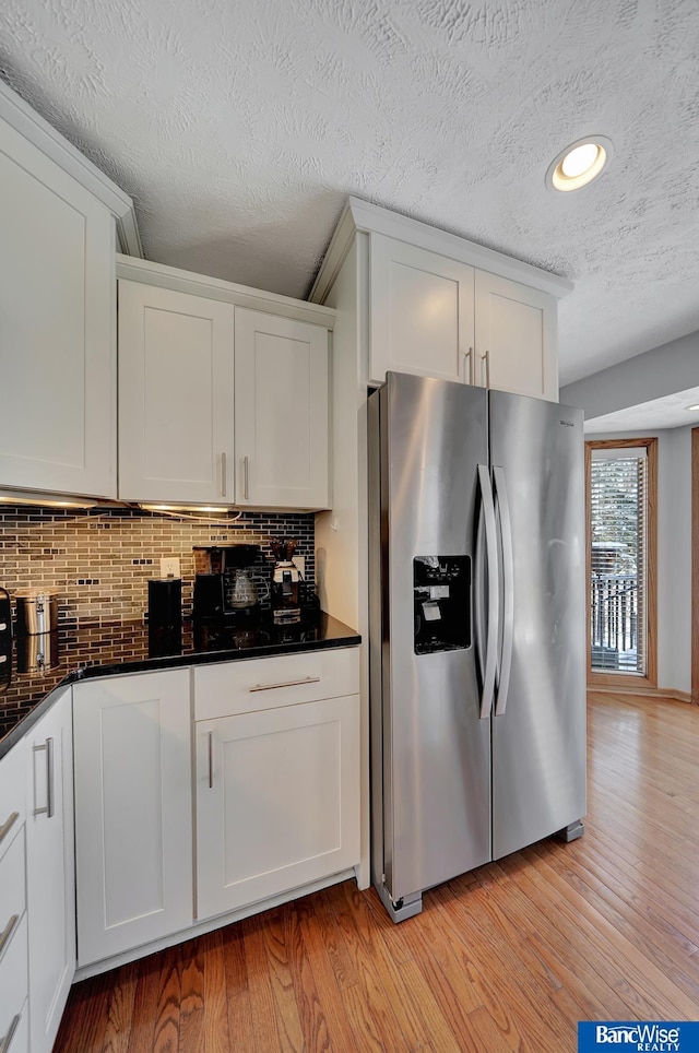 kitchen with decorative backsplash, white cabinetry, and stainless steel fridge with ice dispenser