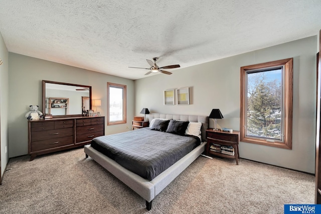 bedroom with a textured ceiling, a ceiling fan, and light colored carpet