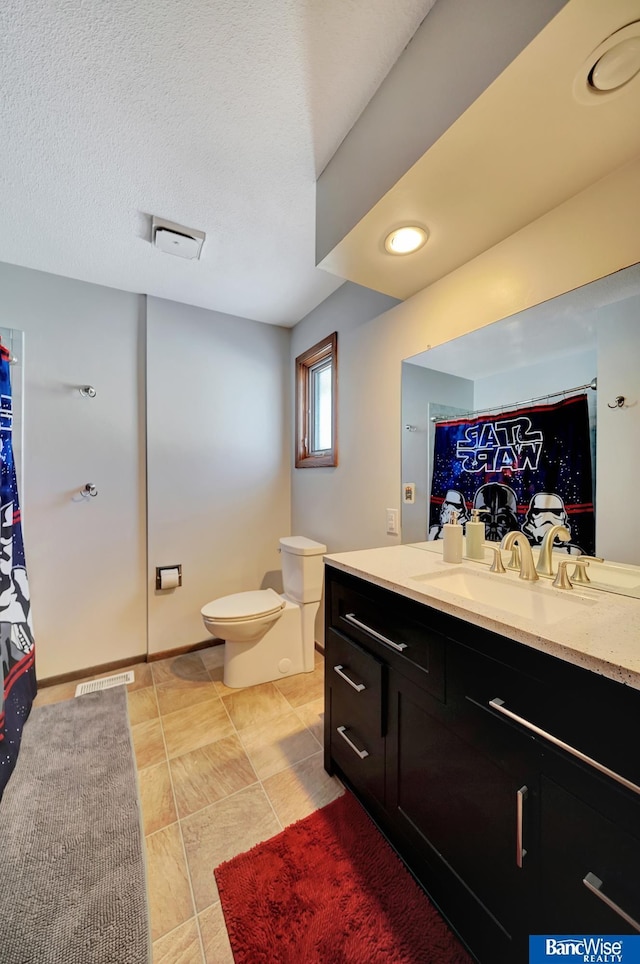 full bathroom with a textured ceiling, toilet, vanity, baseboards, and tile patterned floors